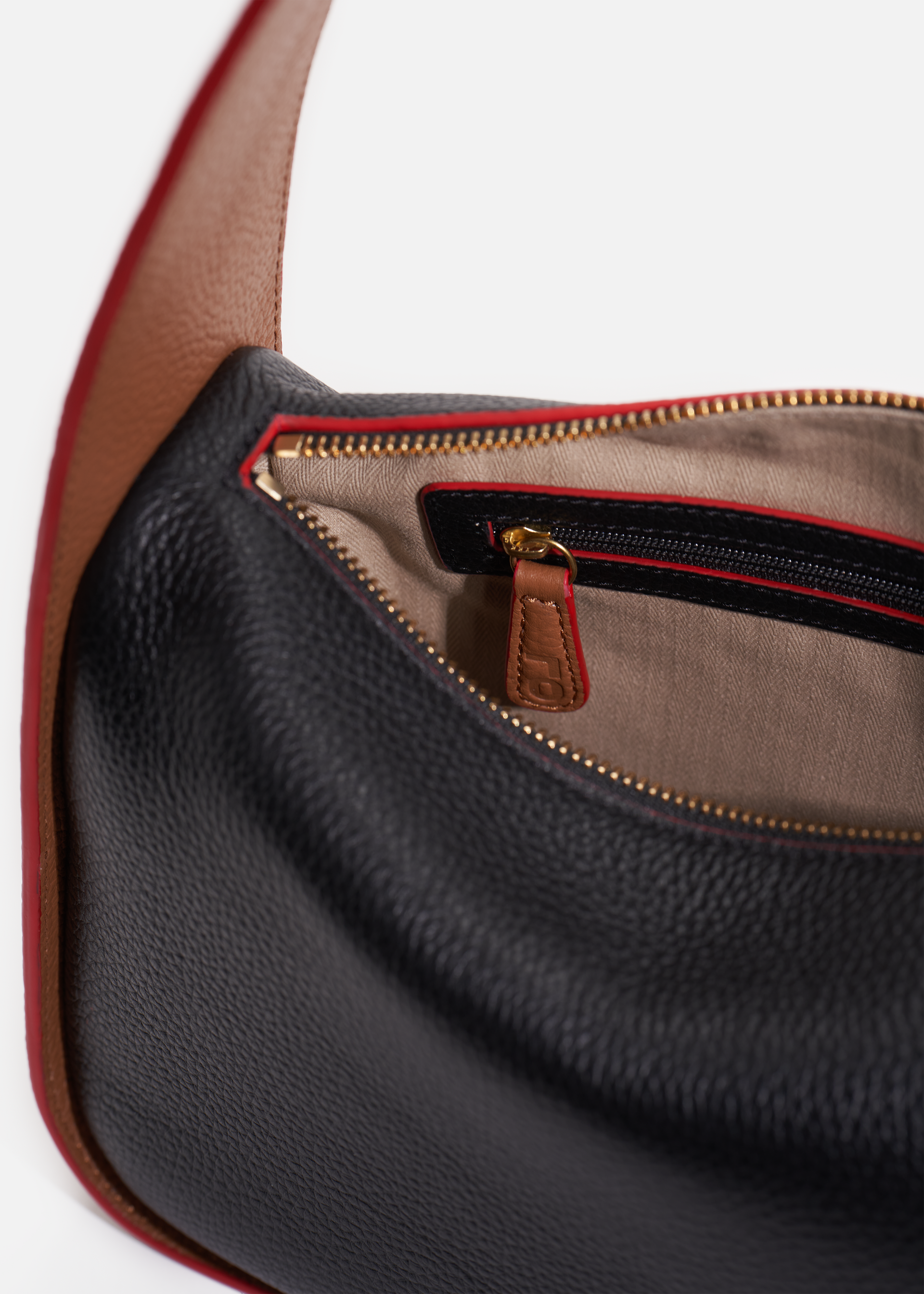 Grete pebble leather shoulder bag in black / caramel with red edge paint