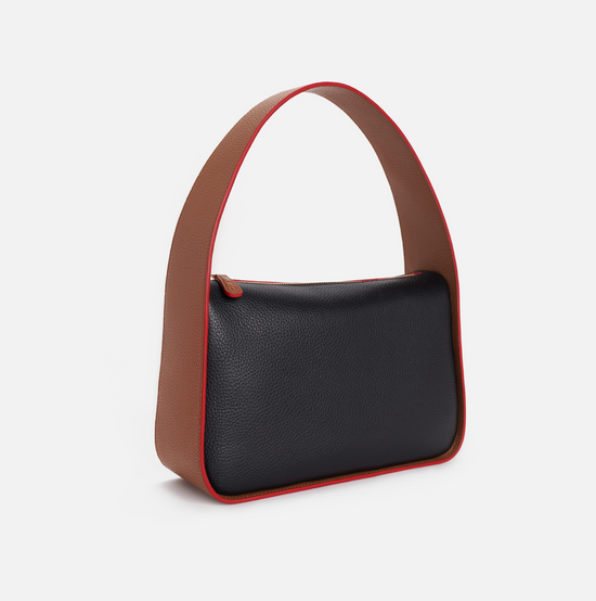 Grete pebble leather shoulder bag in black / caramel with red edge paint